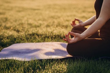 Çimde çiğ taneleriyle güneşli bir sabahta nilüfer pozisyonunda yoga yapan kadın. Sağlıklı yaşam tarzı kavramı. Sabah meditasyonu, rahatlama. Yumuşak seçici odaklanma. Boşluğu kopyala.