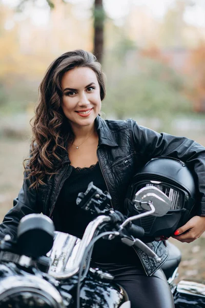 Fiatal Gyönyörű Motoros Lány Fekete Bőrdzsekiben Egy Motorkerékpáron Sisakkal Kezében — Stock Fotó
