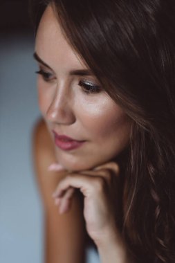 32 yaşında kahverengi gözlü esmer bir kadının yakın plan portresi. Beyaz arka planda siyah bluzlu güzel sağlıklı saçları var. Yumuşak seçici odak.