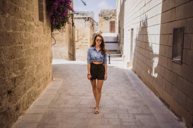 Malta 'nın Mdina şehrinde eski bir sokakta yürüyen bir kadın.