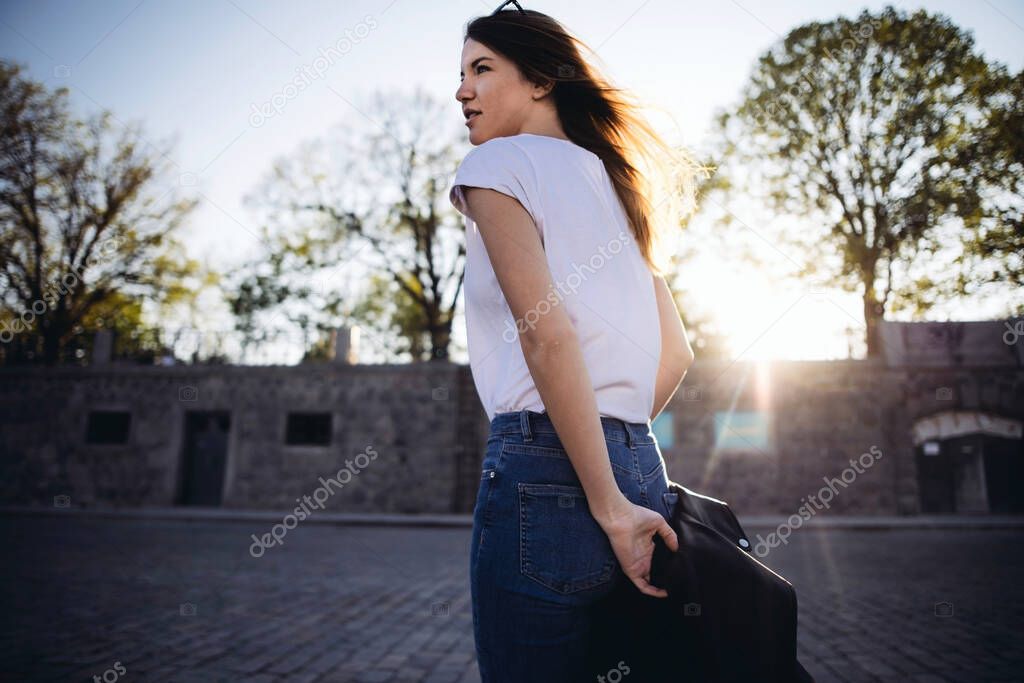Woman with fluttering hair looking back at sunset