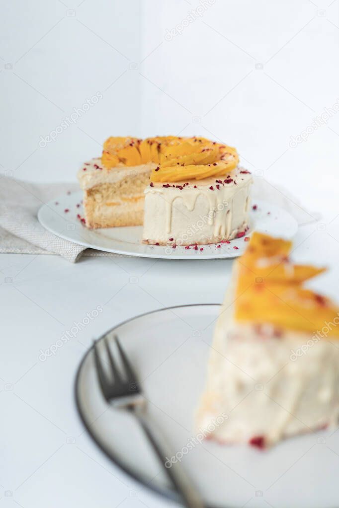 Fresh mango cake with soft cream, topped with white chocolate and sprinkled with dried raspberries