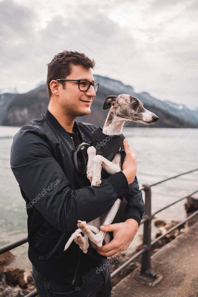 Man holding a small whippet dog in his arms