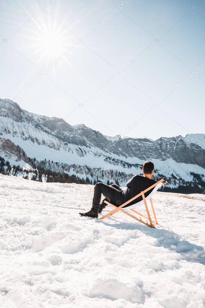 A man is resting on a lounger in the middle of the Swiss mountains