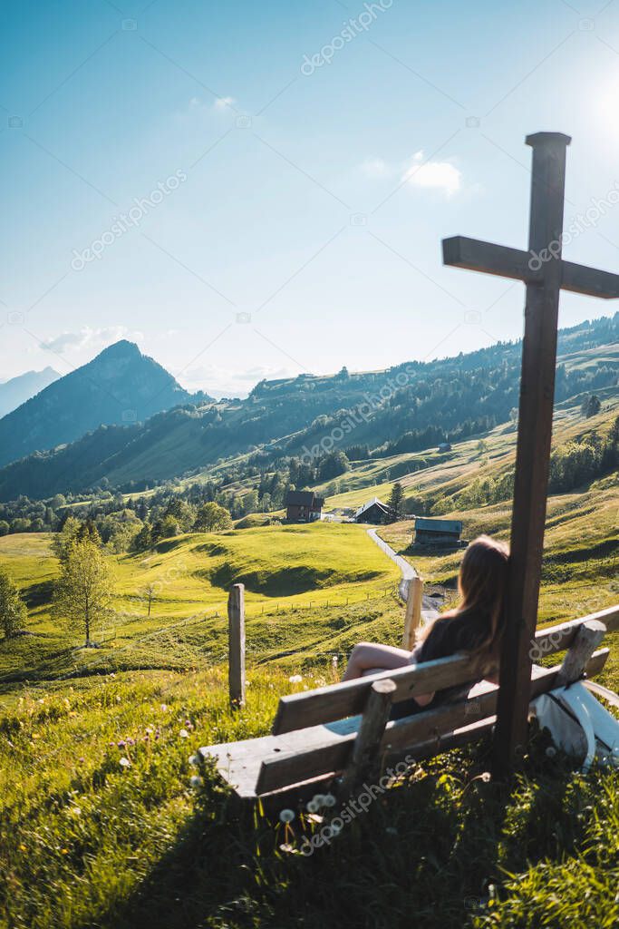 Woman sitting on a bench in the middle of swiss mountains