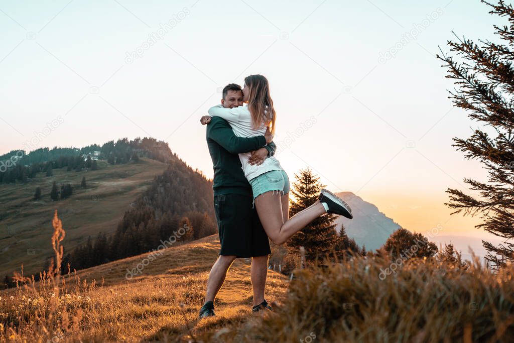Couple embracing on a meadow at sunset in the Swiss mountains