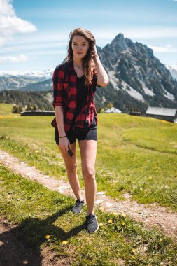Dağlarda yürüyüş yapan ekose gömlekli, dalgalı saçlı, gülen kadın. İsviçre