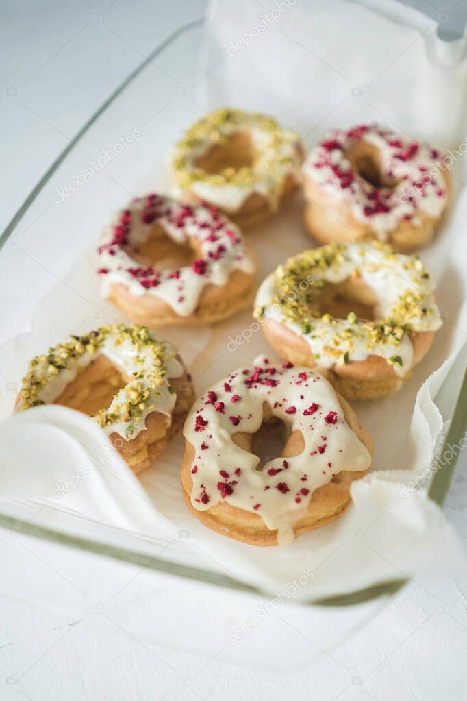 Profiteroles with egg yolk cream sprinkled with white chocolate and sprinkled with raspberries and pistachios