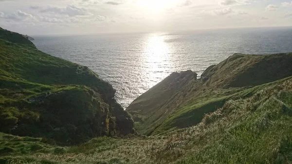 Rochers couverts d'herbe avec l'océan en arrière-plan au crépuscule — Photo