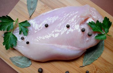 Biberli tavuk fileto, maydanoz ve ahşap bir tahtada defne yaprağı.