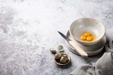 Kırık bıldırcın yumurtaları gri arka planda seramik bir kasede. Üst görünüm, metin için yer.