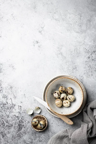Ovos de codorna em uma tigela de cerâmica em um fundo cinza, lugar para texto . — Fotografia de Stock