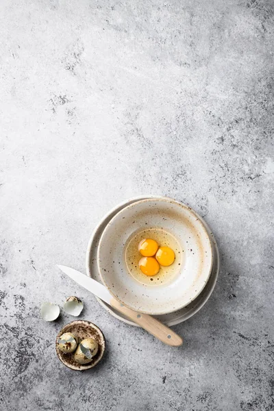 Ovos de codorna quebrados em uma tigela de cerâmica em um fundo cinza. Vista superior, lugar para texto . — Fotografia de Stock