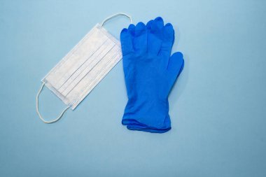 Mavi arka planda tıbbi maskeler ve mavi tıbbi eldivenler.