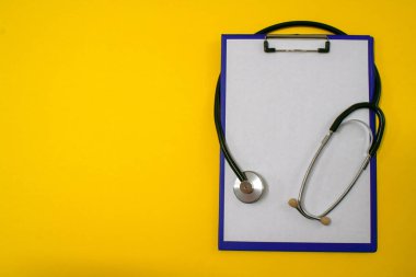Sarı arkaplanda steteskop ve mor klasör tableti