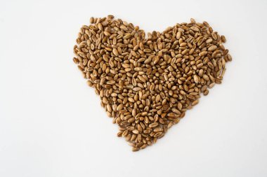 Beyaz arka planda kalp şeklinde buğday taneleri, görüntünün ortasında doğal kurumuş taneler, izole buğday taneleri, aşk