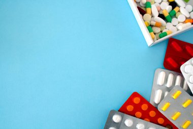 Beyaz bir kutuda renkli tabletler ve kapsüller, bir pakette tabletler, görüntünün çevresi etrafında, mavi arkaplan üzerindeki metnin altında boş bir sol ve merkezle yer alır.