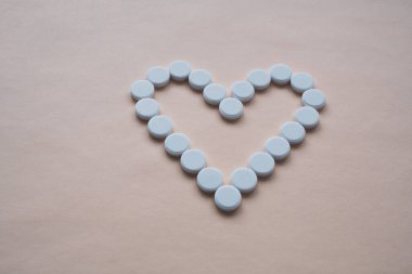 Pembe arka planda kalp şeklinde yuvarlak beyaz haplar, ortada haplar var, izole edilmiş, mesaj için boş bir alan var.