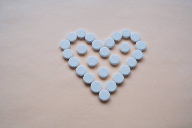 Pembe arka planda kalp şeklinde yuvarlak beyaz haplar, ortada haplar var, izole edilmiş, mesaj için boş bir alan var.