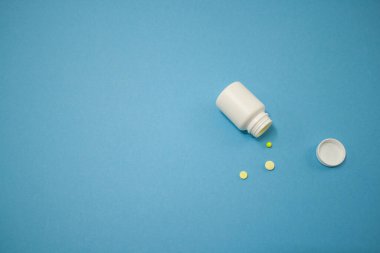 Renkli haplar ve kalp şeklinde kapsüller, soluk mavi arkaplandaki kavanozdan, görüntünün sol tarafında yer alan, metin, aşk ve izole edilmiş bir alan.