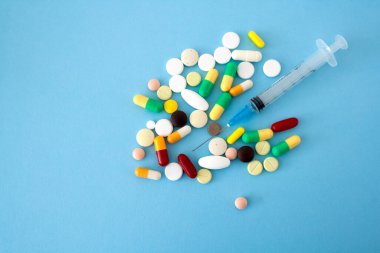 Renkli haplar ve kalp şeklinde kapsüller, soluk mavi arkaplandaki kavanozdan, görüntünün sol tarafında yer alan, metin, aşk ve izole edilmiş bir alan.