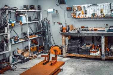 Garaj, sökülmek için servis alanı, motosiklet tamiri, araba servis istasyonu. Atölyenin içinde büyük bir tezgah ve rafla birlikte, duvardaki anahtarı işlemek için çok sayıda alet var.