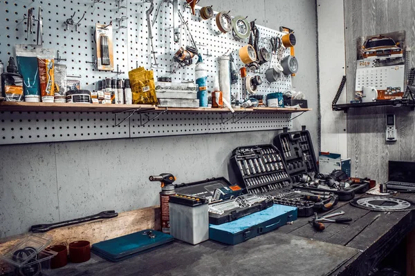 All'interno del laboratorio. Ampio banco da lavoro e utensili per lavorare sul tavolo primo piano. Spazio di lavoro per meccanico con chiavi, pinze su parete metallica. Garage per la riparazione di moto, stazione di servizio auto . — Foto Stock