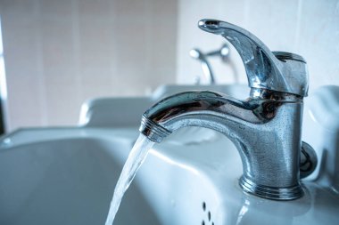 Suyu akan musluk. Musluk, resimde kimse olmadan suyun akmasına izin veriyor..