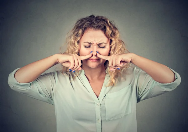 Woman pinches nose with fingers looks with disgust something stinks — Stockfoto