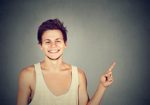 Feliz joven sonriente apuntando al espacio en blanco — Foto de Stock