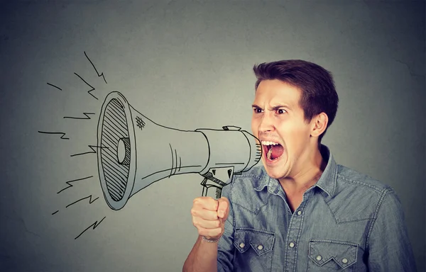 Angry young man holding screaming in megaphone — Stock Photo, Image