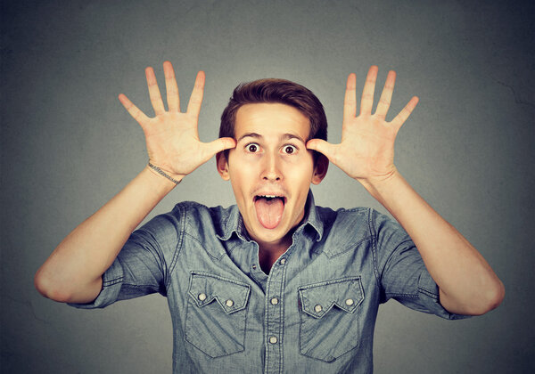 man, sticking out tongue at you, thumbs hands on temple 