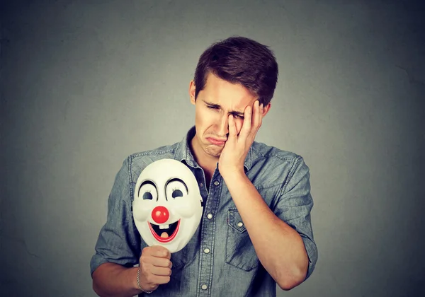 Jeune homme triste avec masque de clown heureux — Photo