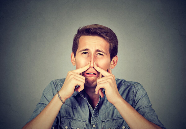 man pinches nose looks with disgust something stinks bad smell 