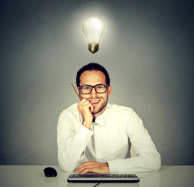 adam hea üzerinde ampul ile bilgisayar klavyesi önünde oturan