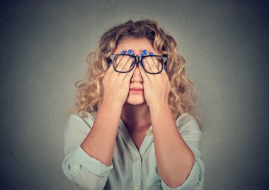 woman in glasses covering face eyes with both hands