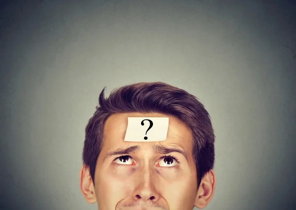 Thinking man with question mark on gray wall background — Stock Photo, Image