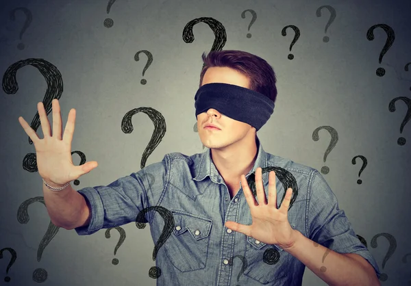 Blindfolded man walking through many question marks — Stock Photo, Image