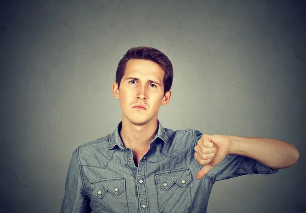 Angry young man showing thumbs down sign, in disapproval — Stock Photo, Image