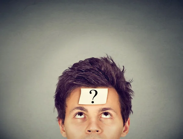 Denkender Mann mit Fragezeichen auf grauem Hintergrund — Stockfoto