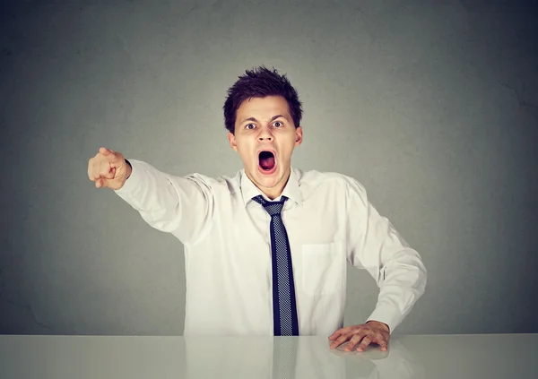 Angry young business man sitting at his desk and screaming — Stock Photo, Image