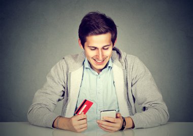 İnternet alışveriş için akıllı telefon kullanarak kredi kartı tutan adam