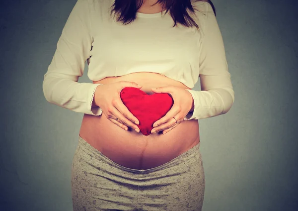 Mulher grávida segurando sinal de coração em sua barriga — Fotografia de Stock