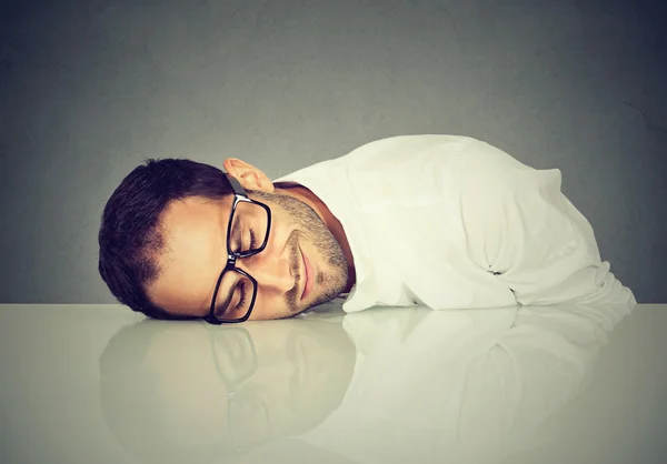 Uomo con gli occhiali che dorme su una scrivania — Foto Stock