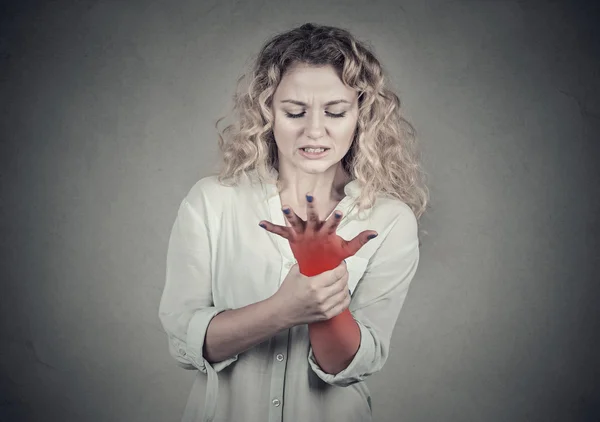 Mujer sosteniendo la muñeca dolorosa. Esguince dolor ubicación en rojo —  Fotos de Stock