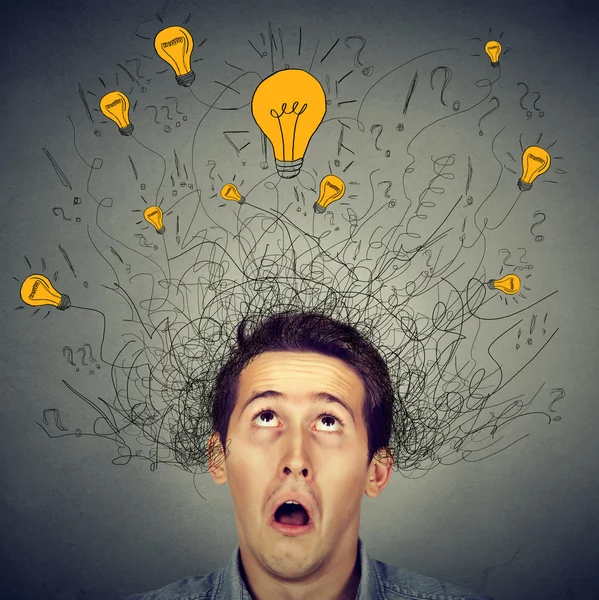 Surprised man with many ideas light bulbs above head looking up — Stockfoto