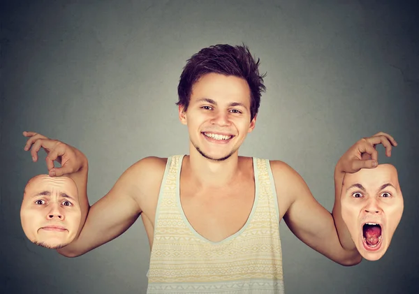 Smiling man holding two different emotion masks — Stock Photo, Image