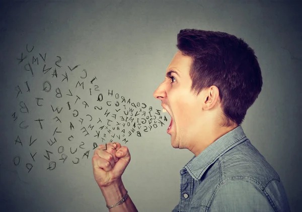 Angry man screaming with alphabet letters flying out of wide open mouth — Stock Photo, Image