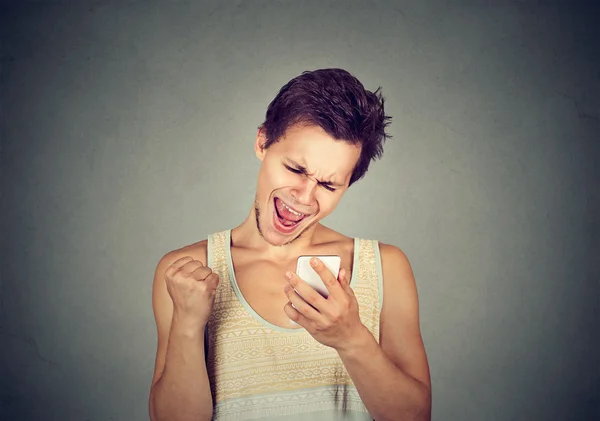 Gelukkig man kijken naar mobiele telefoon pompen vuist viert succes — Stockfoto