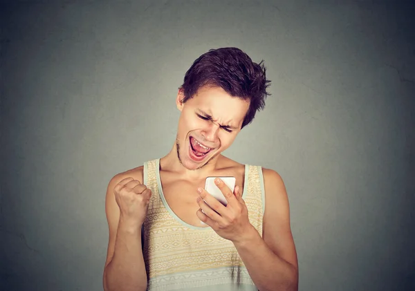 Uomo felice guardando il telefono cellulare pompaggio pugno celebra il successo — Foto Stock